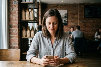 Femme utilisant un smartphone milieu de gamme dans un café urbain au quotidien